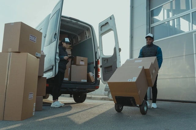 Delivery workers loading and transporting ecommerce packages in a delivery van