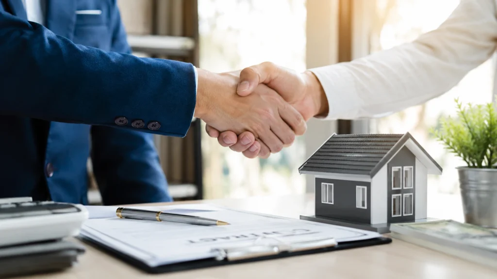 Professionals completing a cash home sale agreement in Washington with house model and signed documents
