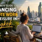 Remote worker using a laptop on a rooftop workspace overlooking the Bangkok skyline at sunset, illustrating the perfect balance between productivity, travel, and leisure in Thailand.