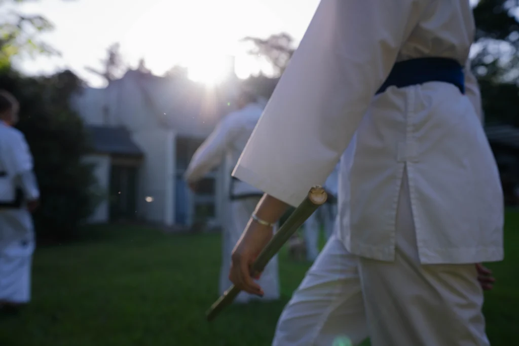 Person practicing coordination-based weapon flow training with a staff during an outdoor martial arts session