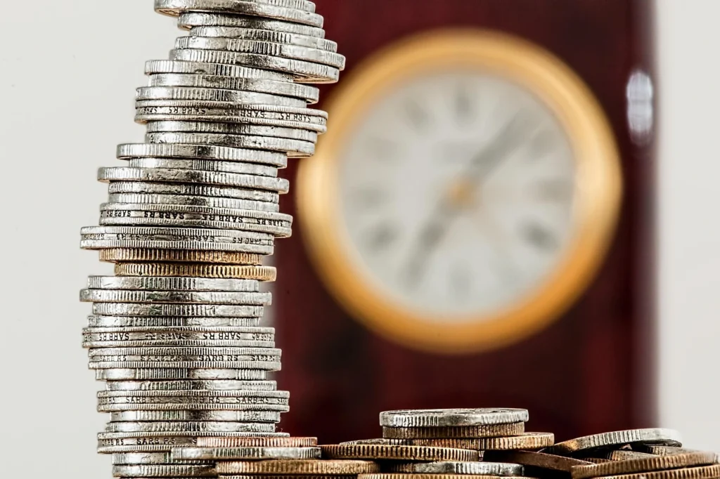 Stack of coins beside a clock representing corporate donations, financial planning, and long-term giving