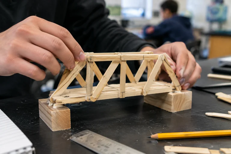 Student building a wooden bridge model as part of a hands-on learning project